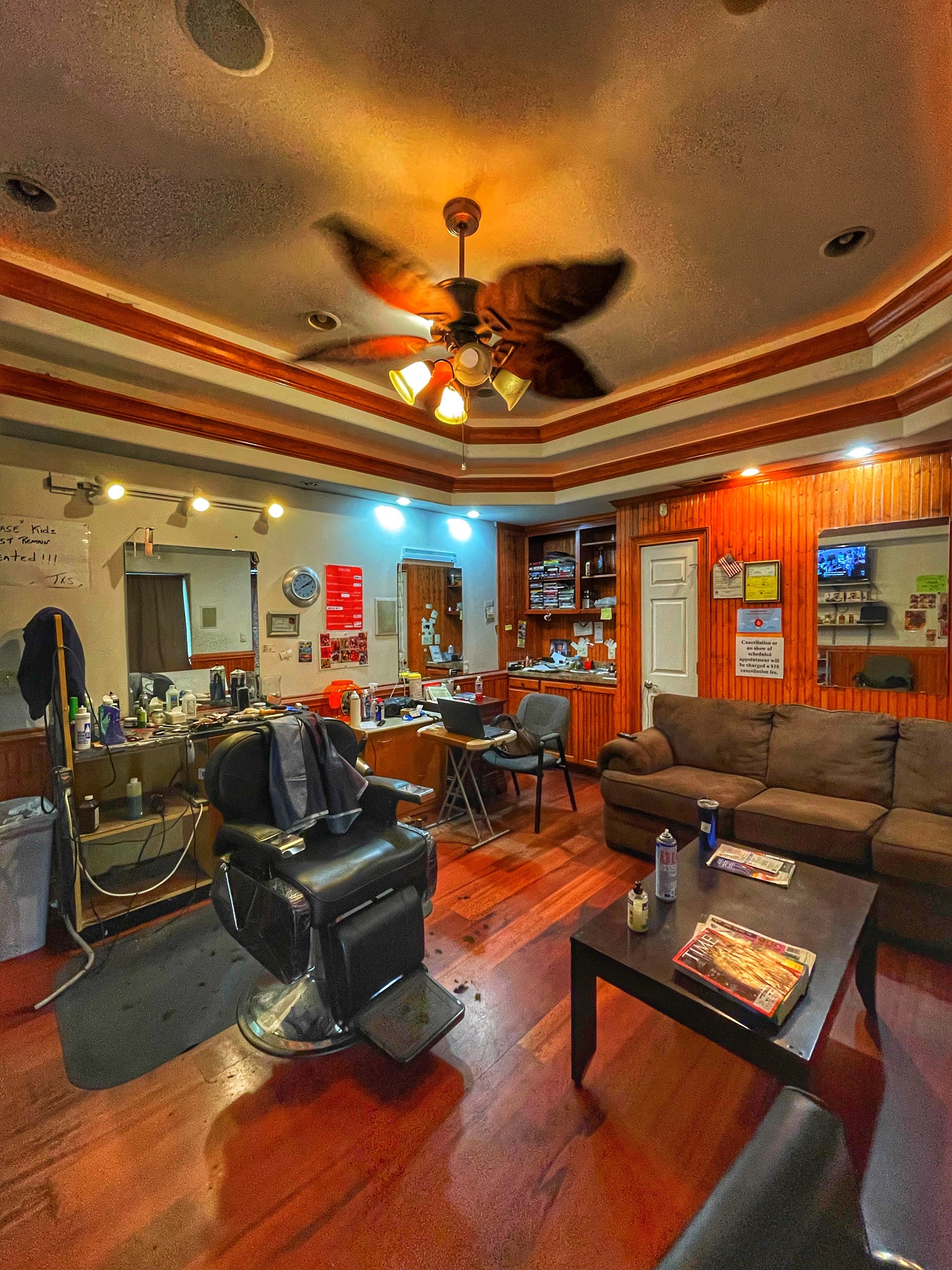 The shop floor with wood floors, a ceiling fan and barber chairs